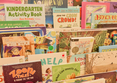 A display shelf filled with colorful childrens books, including titles like Kindergarten Activity Book, Join the Crow Crowd!, The Wish Watch, and Ginger Pye.